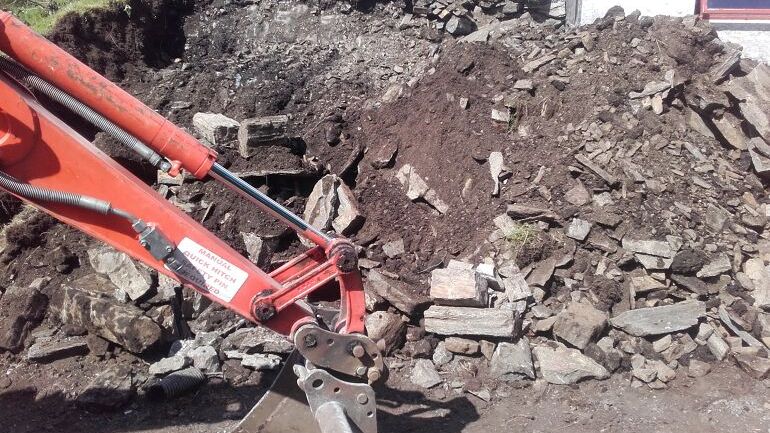 Gravemaskin med en haug av jord og stein